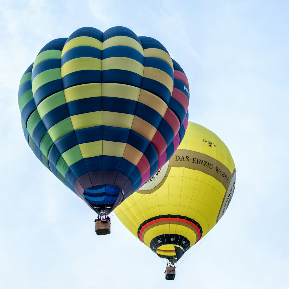 a couple of hot air balloons flying through a blue sky