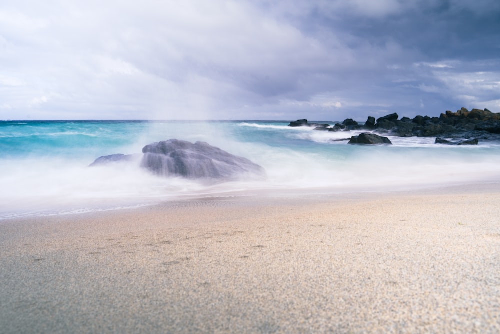 a sandy beach with a large rock in the middle of it