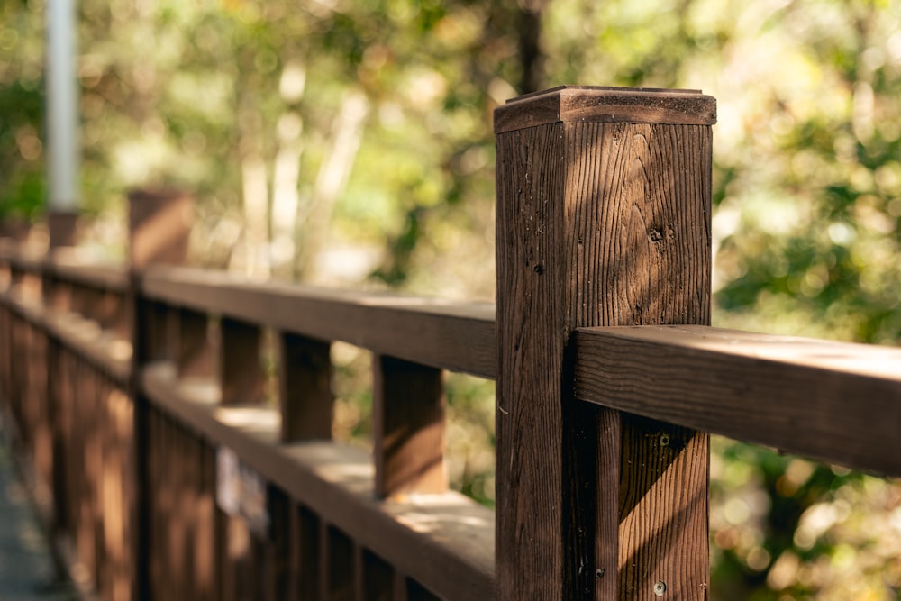 a close up of a wooden fence with trees in the background