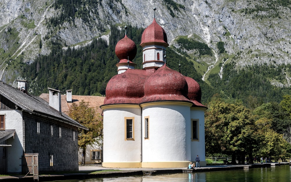 a building with a red dome next to a body of water