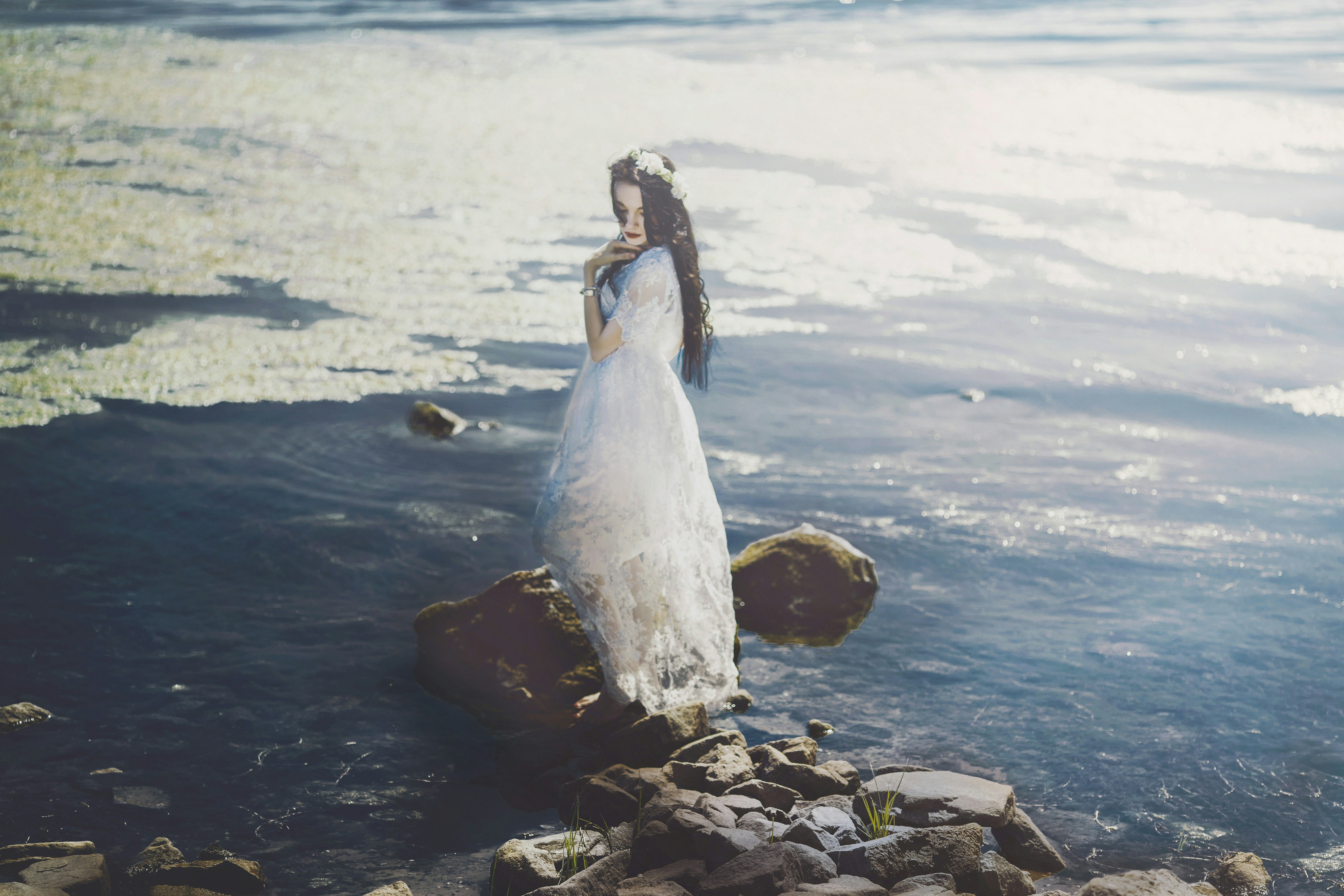 a woman standing on rocks in the water