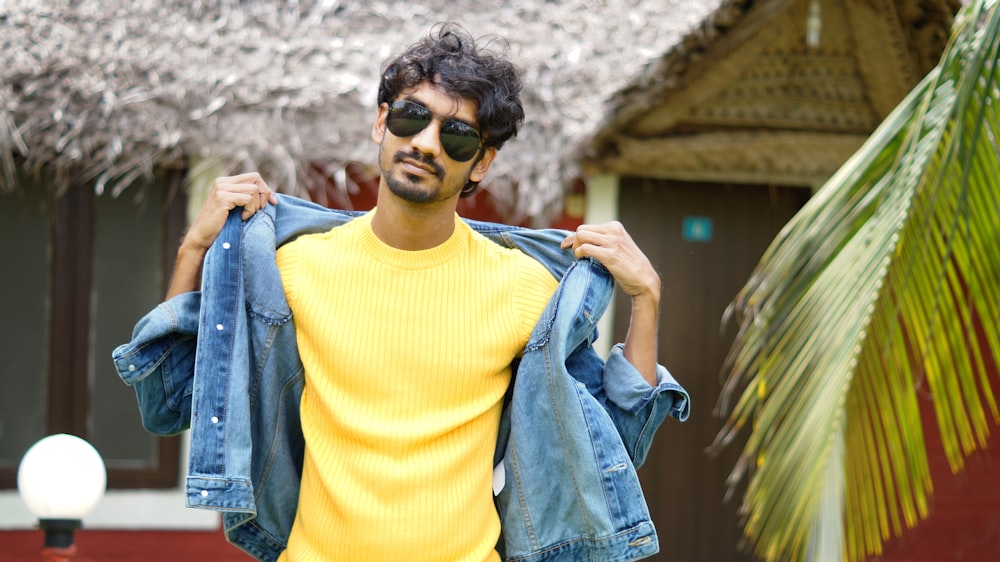 a man in a yellow shirt is holding a jean jacket