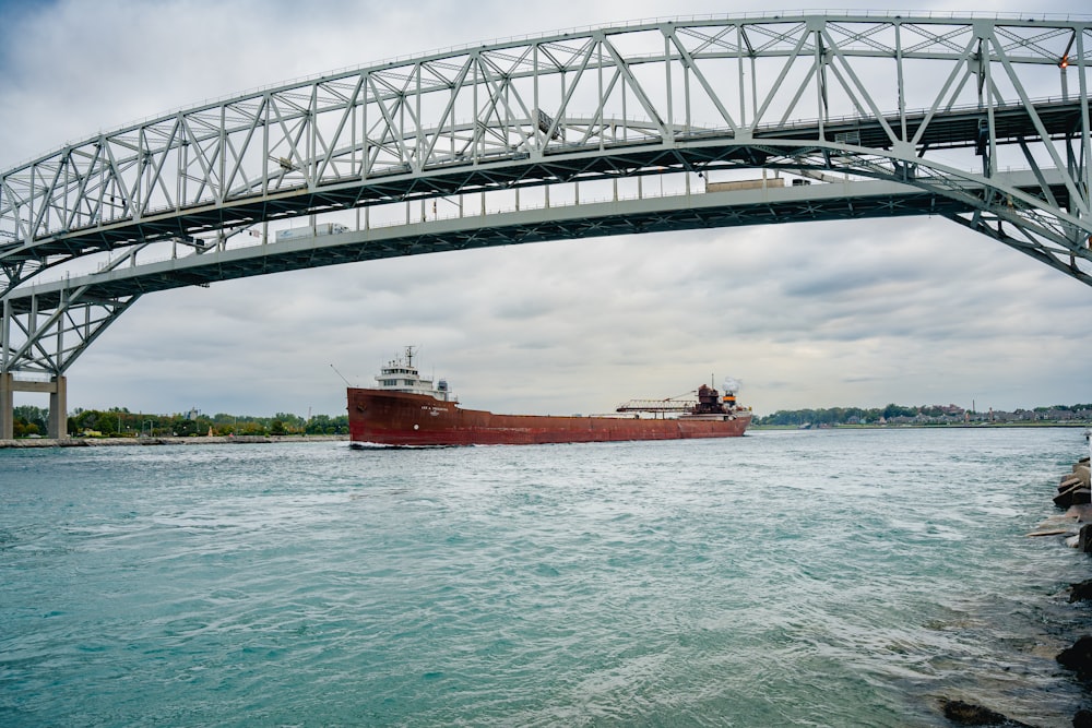 um grande barco sob uma ponte sobre um corpo de água