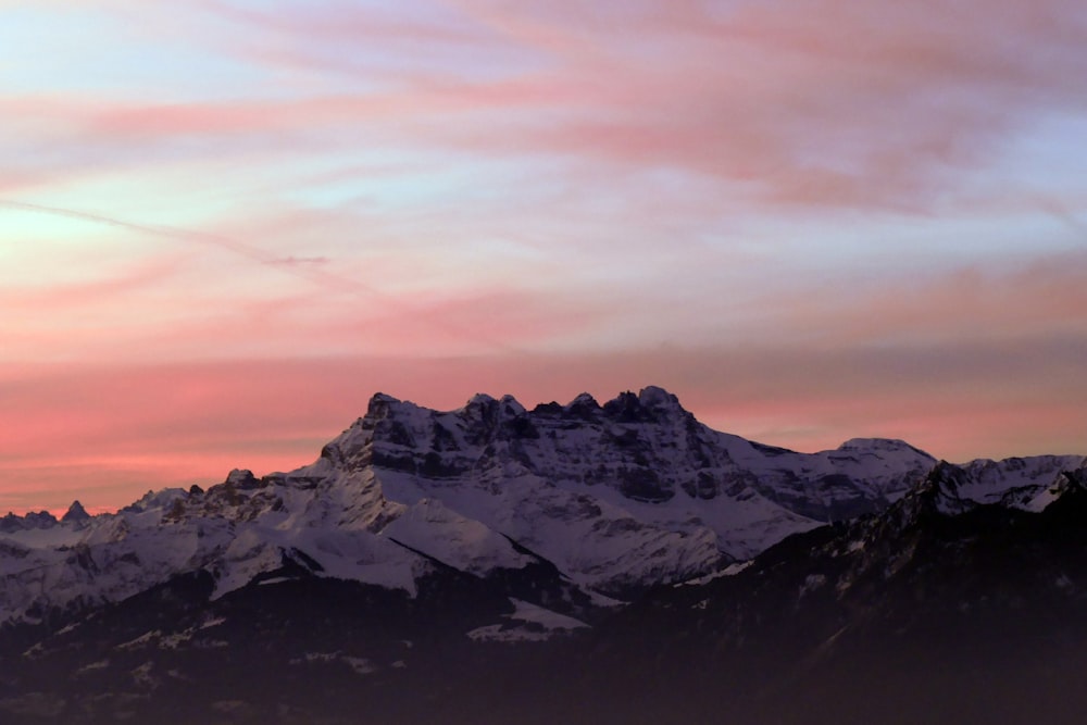 a snow covered mountain with a pink sky in the background