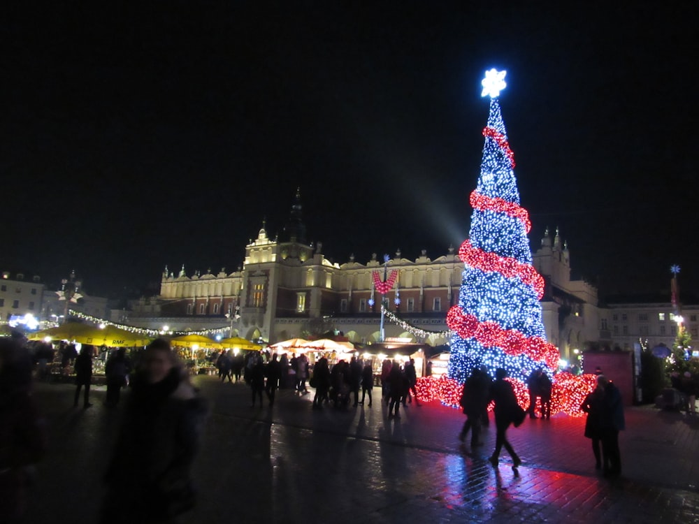 a large christmas tree is lit up in front of a building