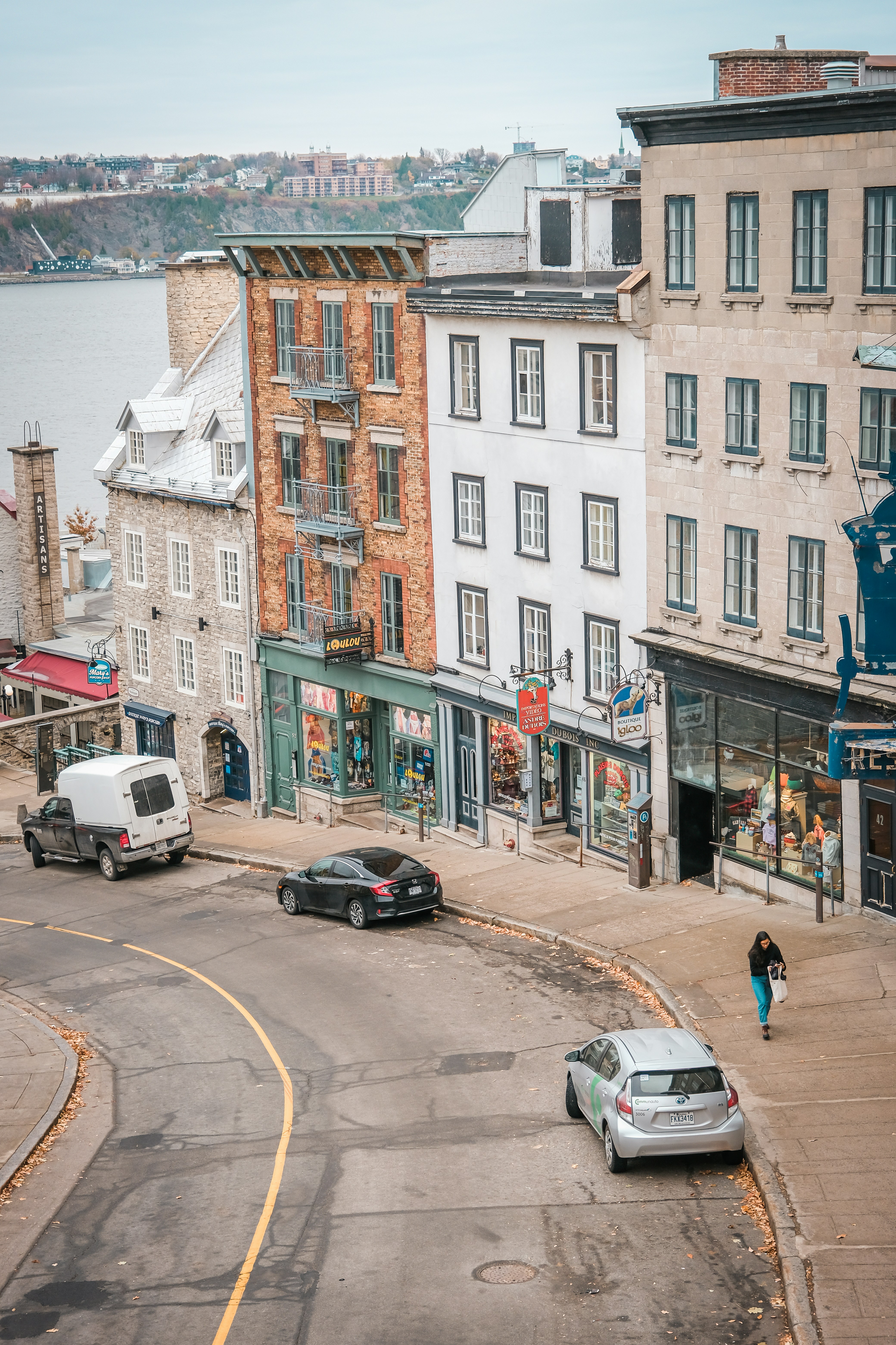 a woman walking down a street next to tall buildings