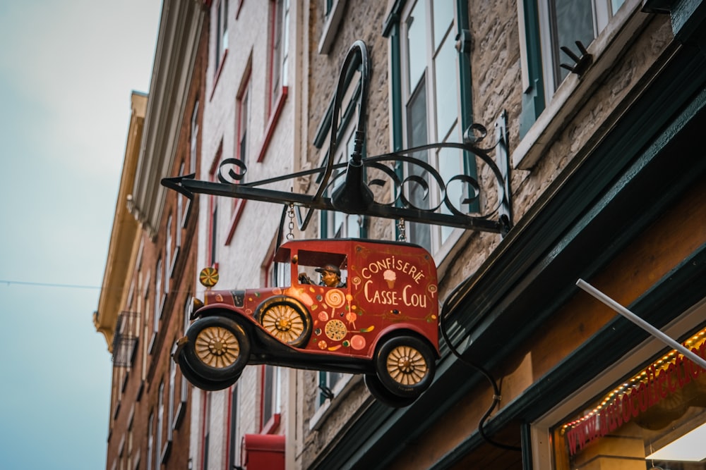 a red truck hanging from the side of a building