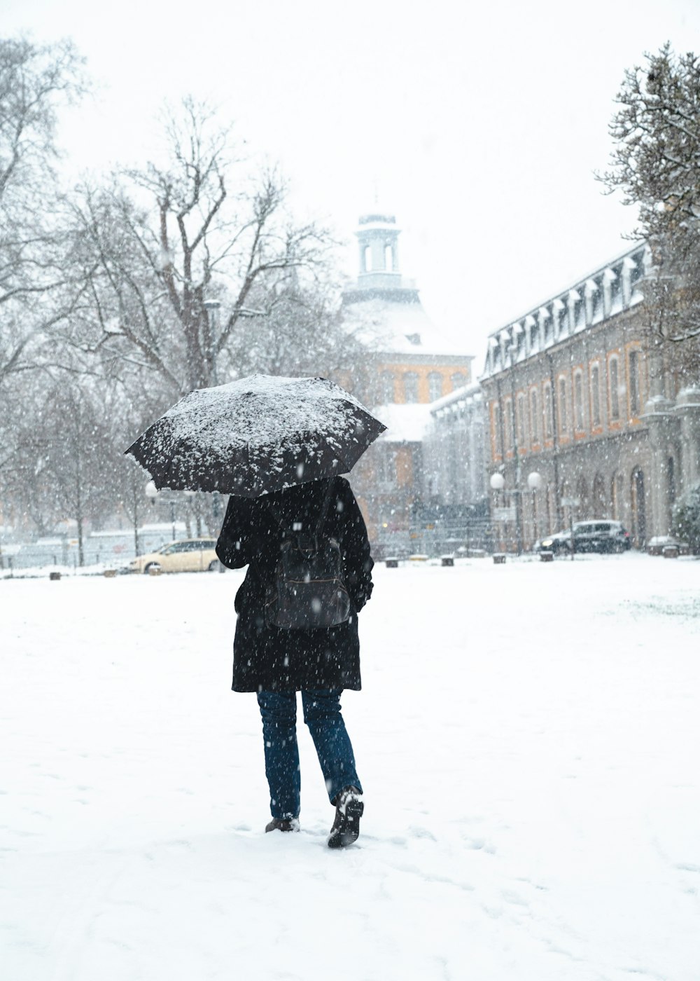 eine Person, die mit einem Regenschirm im Schnee steht