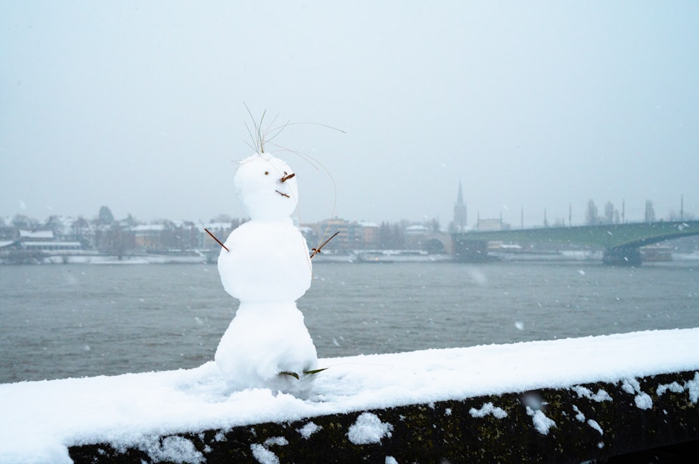 a snowman is standing on the edge of a bridge