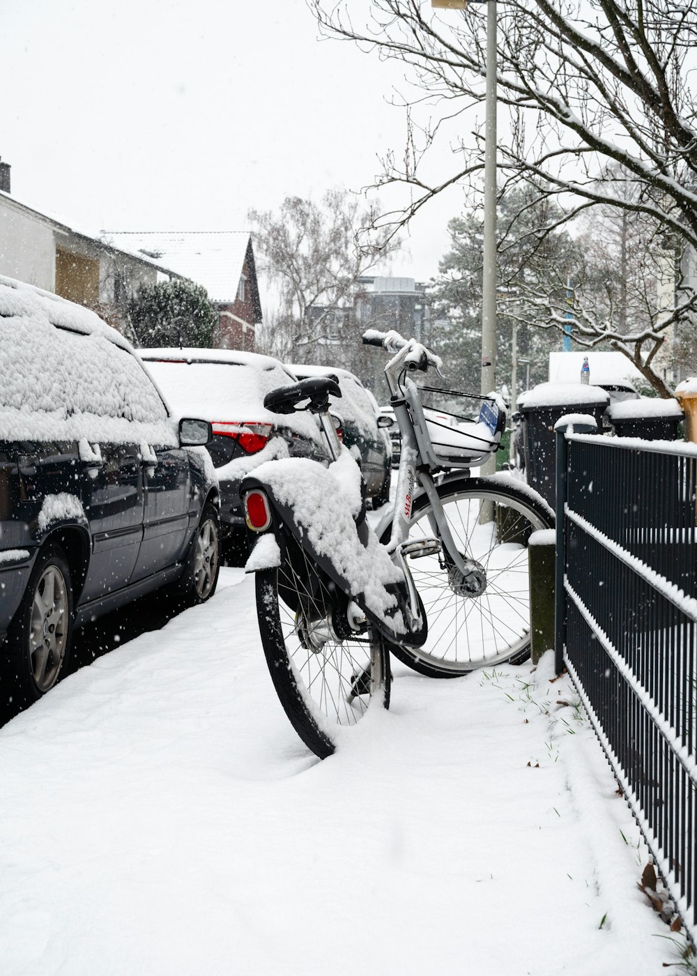 a bicycle is covered in snow next to a fence