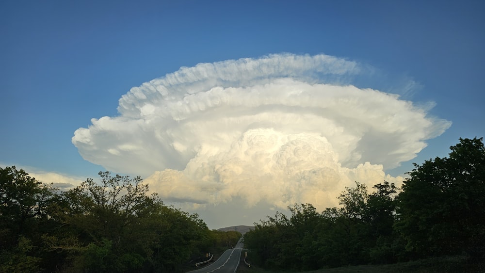 a very large cloud in the sky over a road