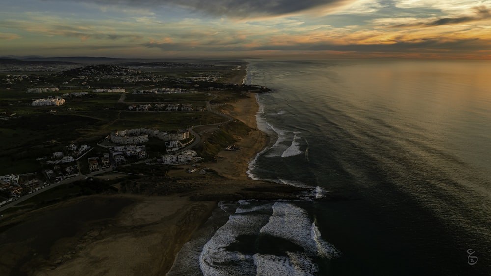 an aerial view of a beach and ocean at sunset