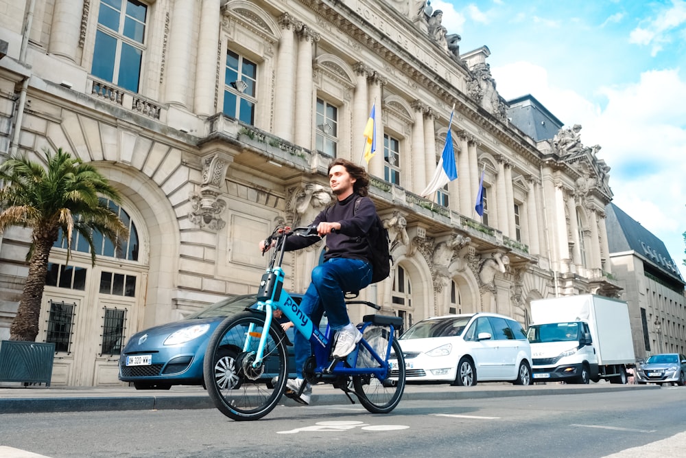 a man riding a blue bike down a street