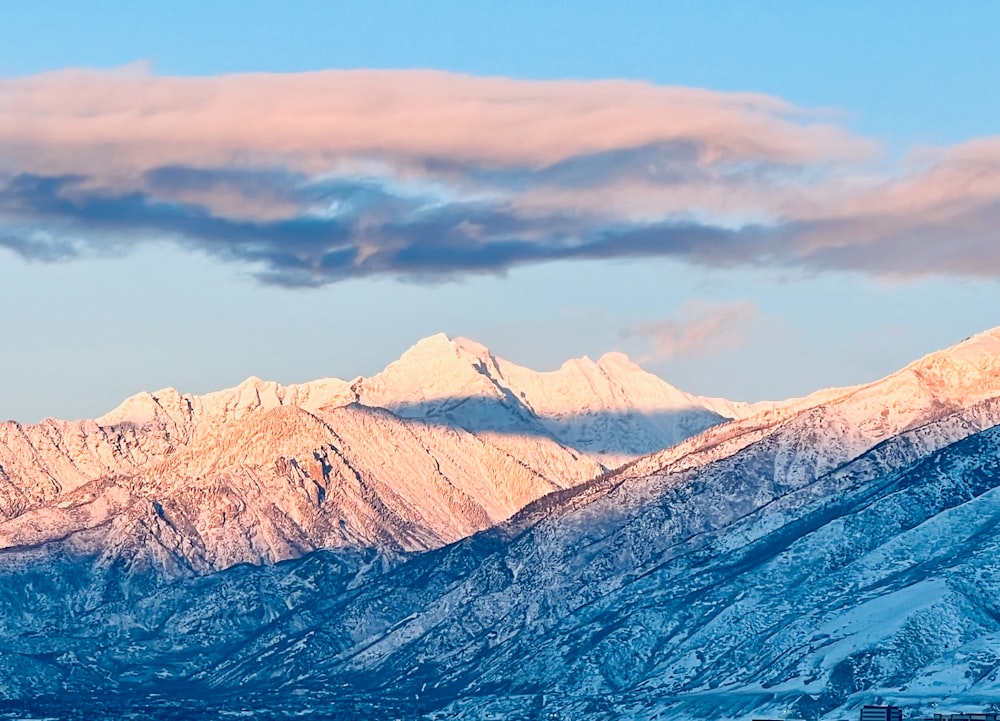 a snow covered mountain range under a blue sky