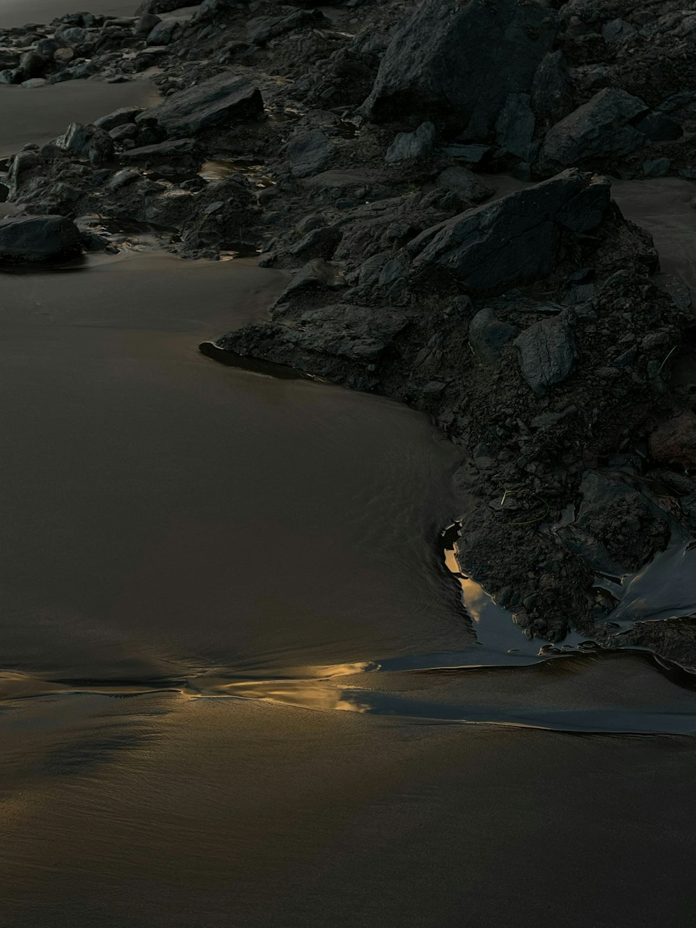 a beach with rocks and water at night