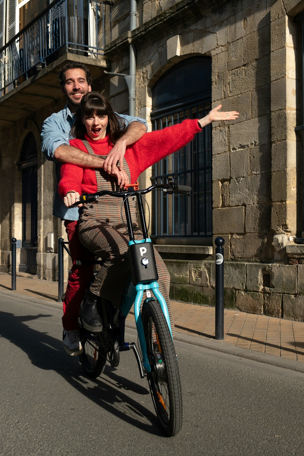 a man and woman riding a bike down a street