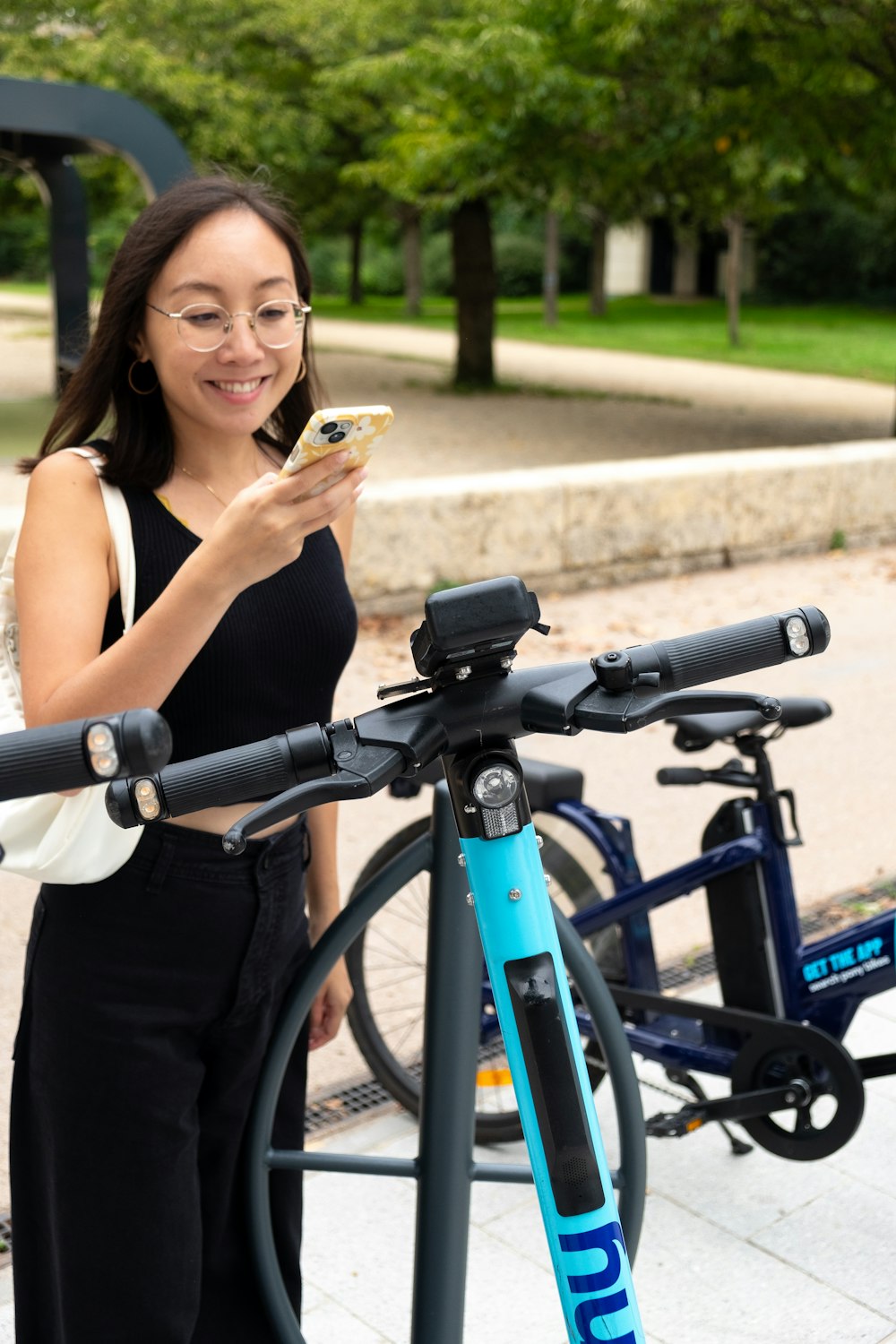 a woman standing next to a bike holding a cell phone