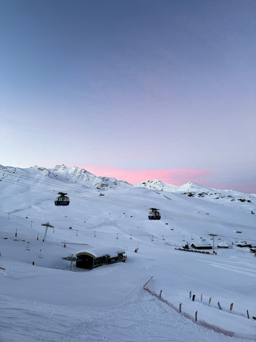 a snow covered ski slope with a ski lift in the distance