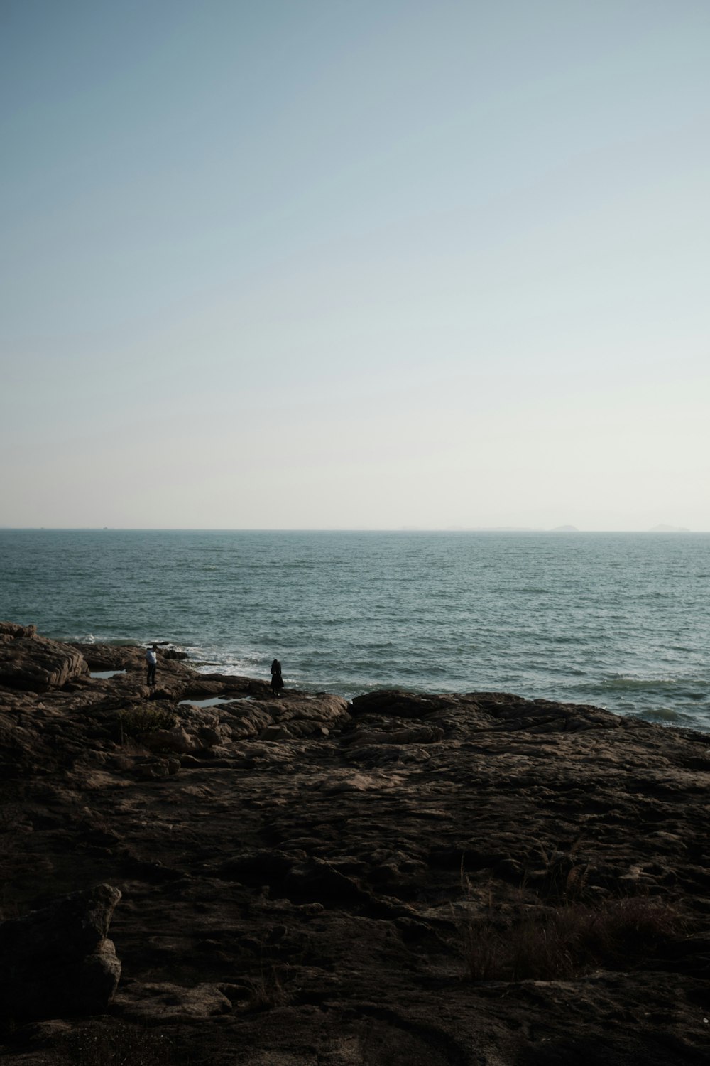 a person sitting on a rock near the ocean