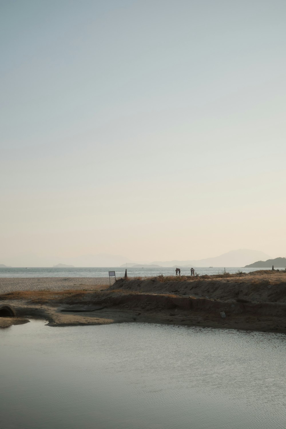 a body of water with a few people standing on the shore