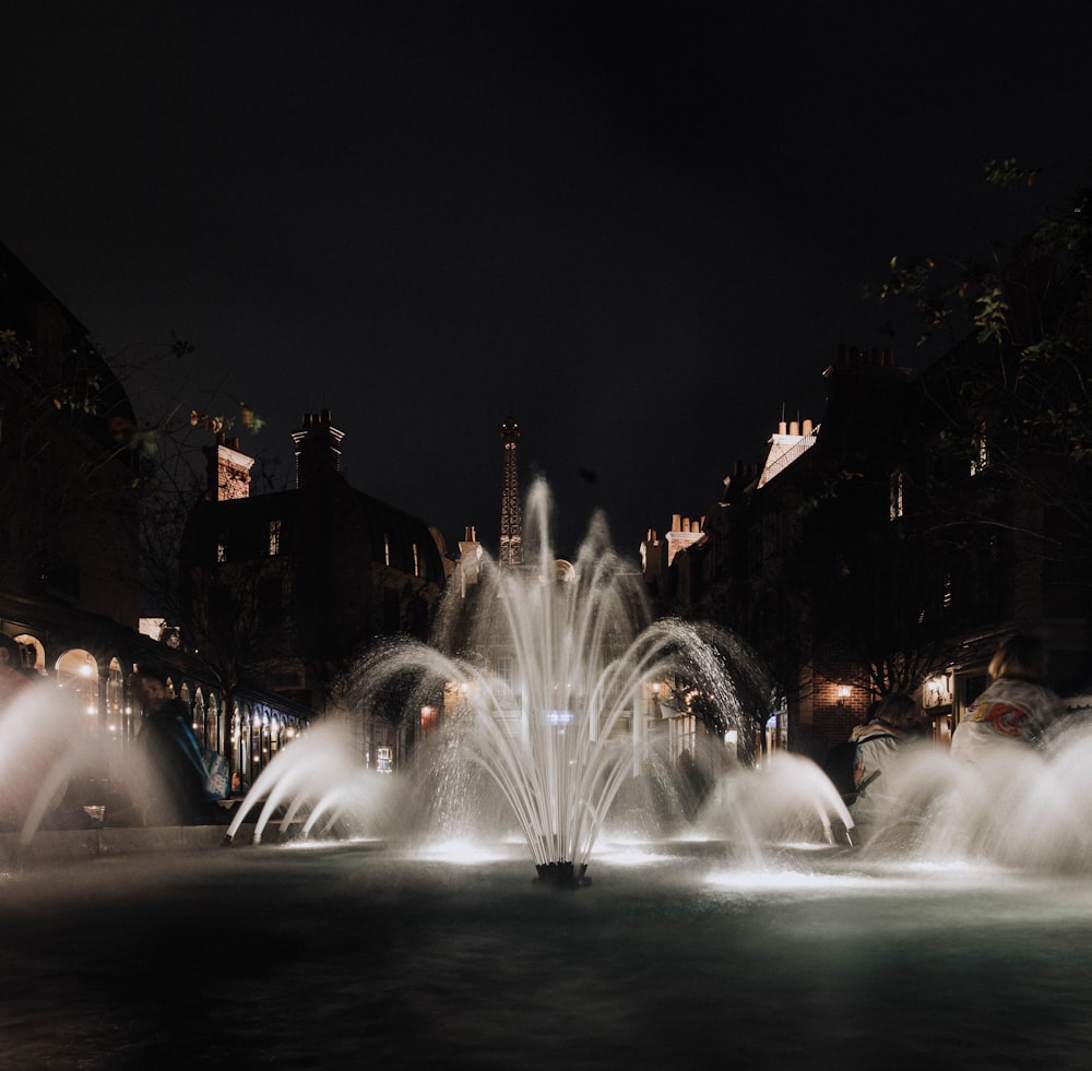 a water fountain in the middle of a city at night