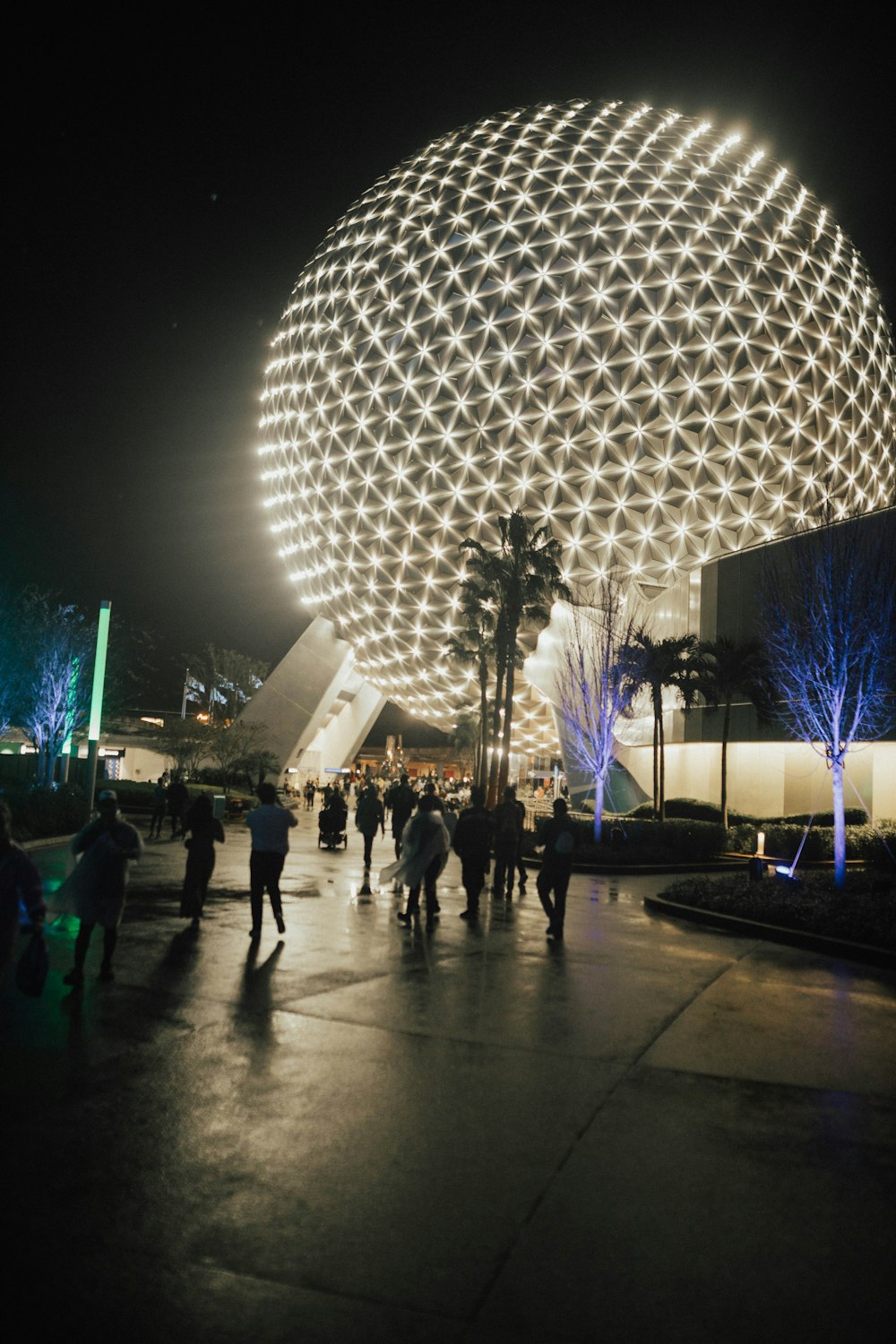 a group of people walking around a building at night