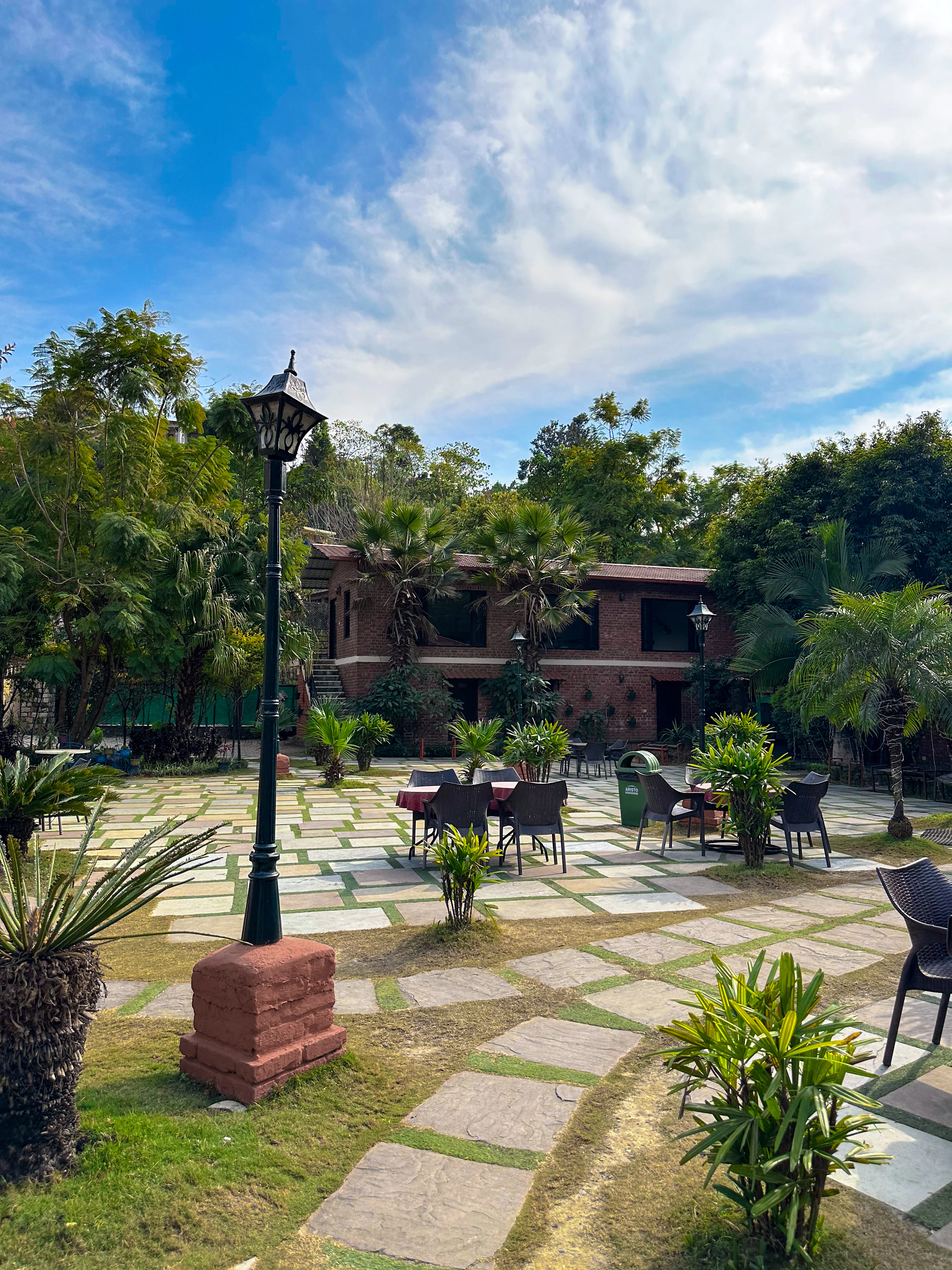 Farmhouse patio with outdoor furniture, lamp posts and plants