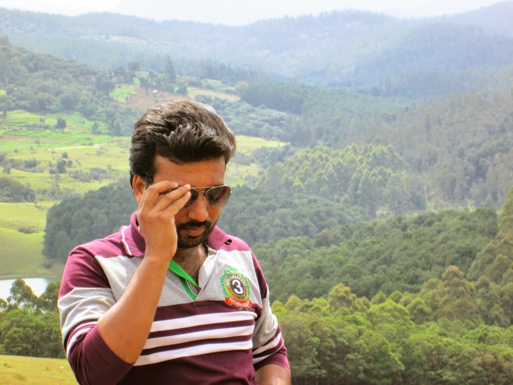 a man in a maroon and white striped shirt is talking on a cell phone