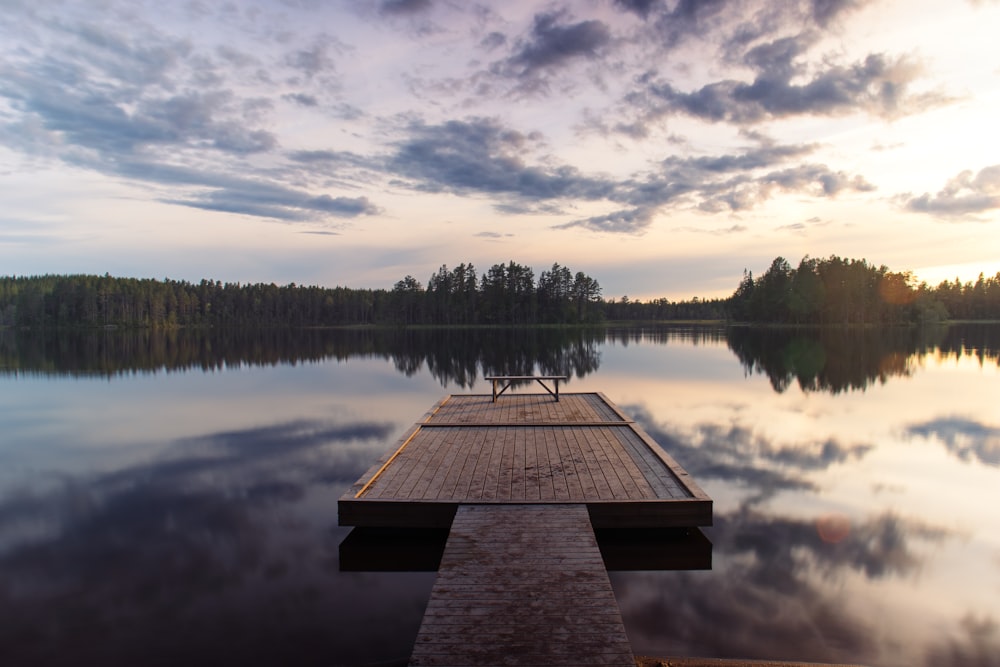 a dock sitting on top of a lake next to a forest