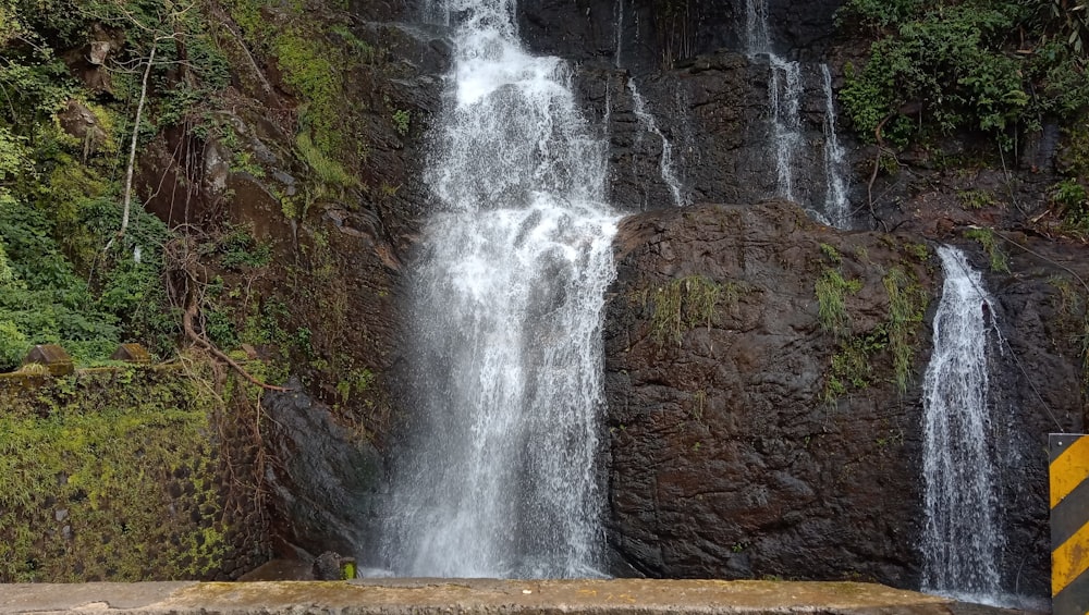 a waterfall with a yellow caution sign in front of it