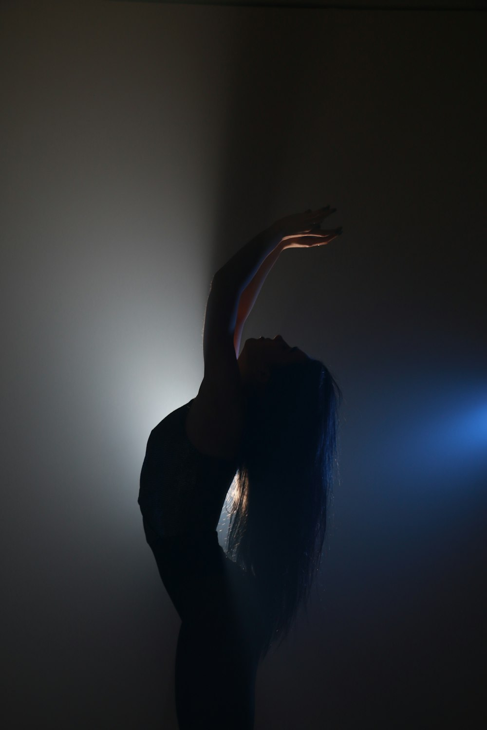 a woman standing in the dark with her arms outstretched