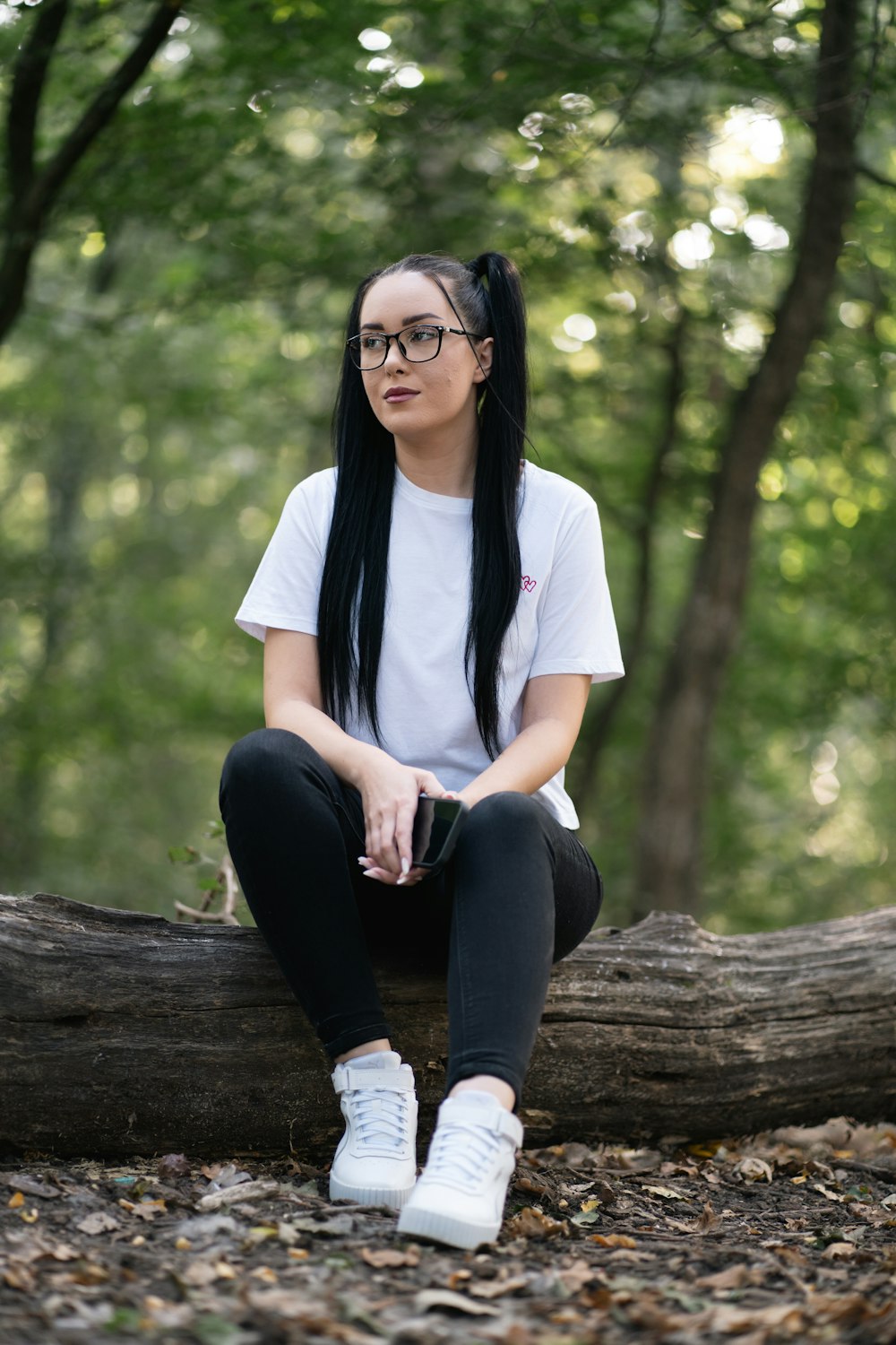 a woman sitting on a log in the woods