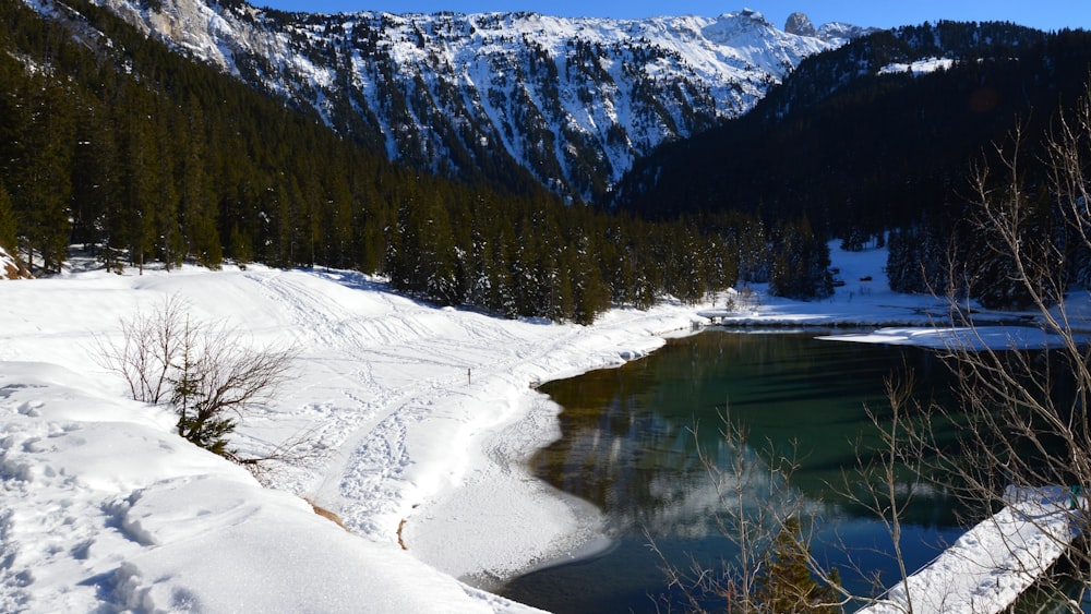 a lake surrounded by snow covered mountains and trees