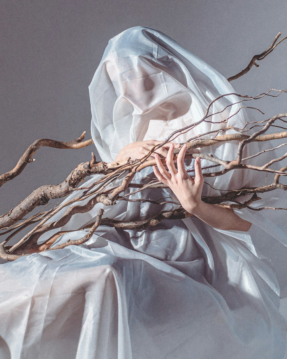 a woman in a white dress with branches on her head