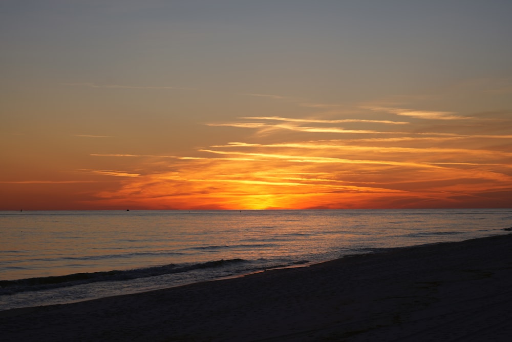 the sun is setting over the ocean on the beach