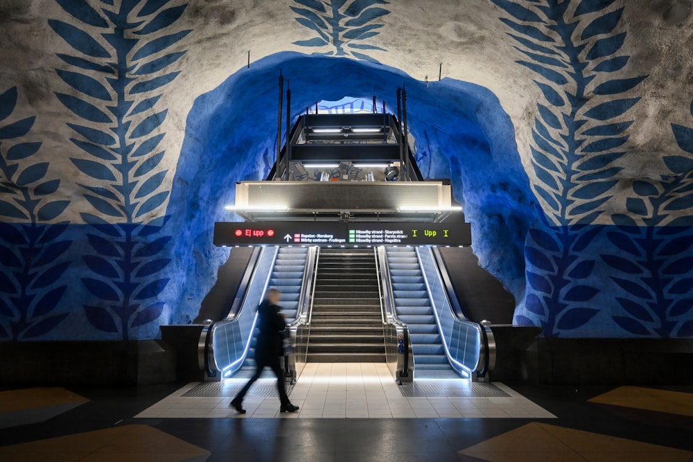 an escalator in a building with a mural on the wall