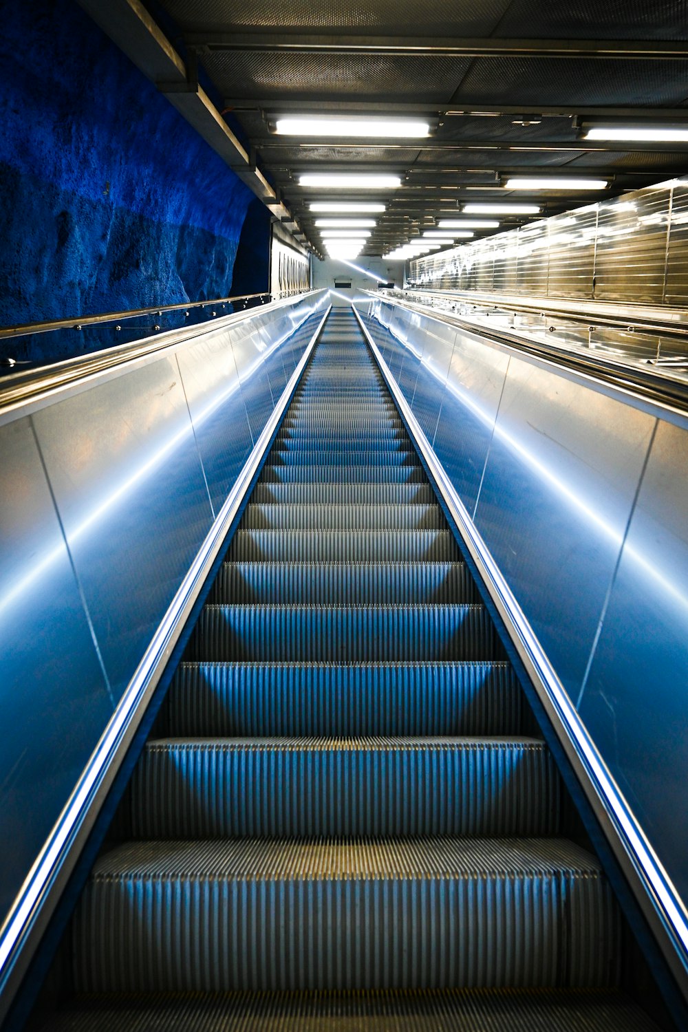 uma escada rolante em uma estação de metrô com paredes azuis