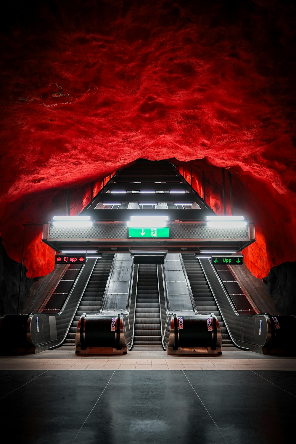 una estación de metro subterránea con escaleras mecánicas y paredes rojas