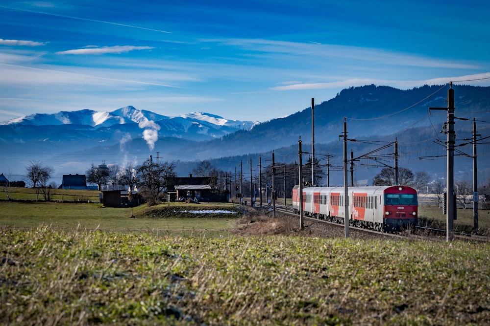 a train traveling through a rural countryside with mountains in the background