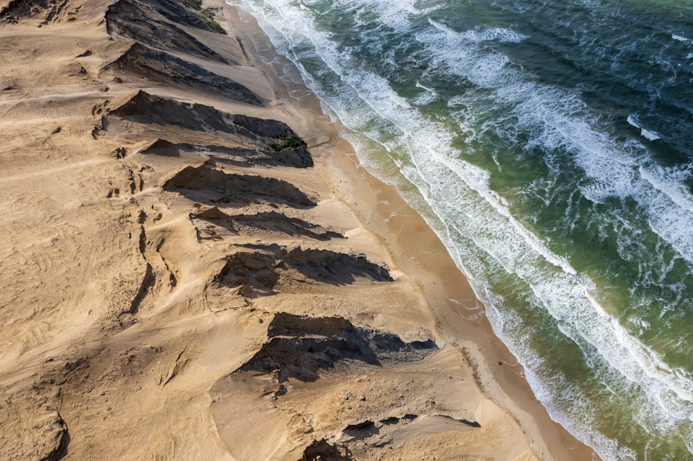 an aerial view of a beach with waves crashing on the shore