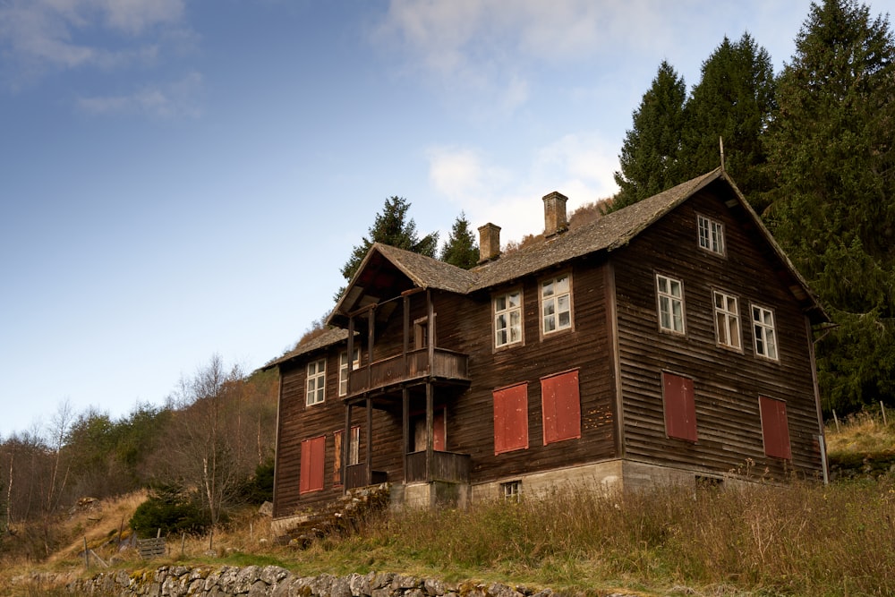 Une vieille maison en bois avec des volets rouges aux fenêtres