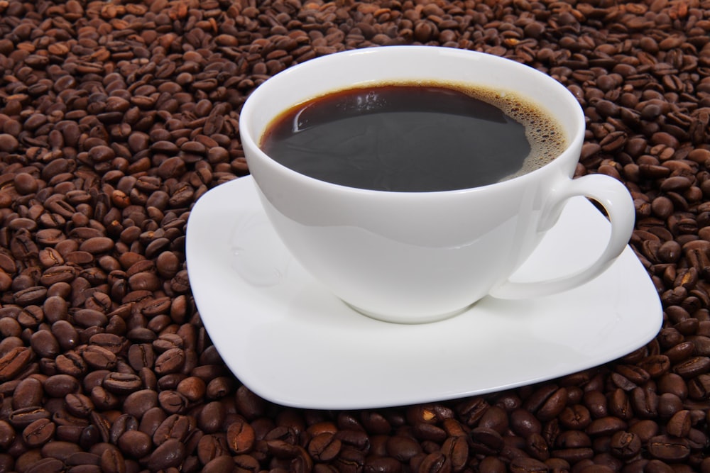 a cup of coffee sitting on top of a pile of coffee beans