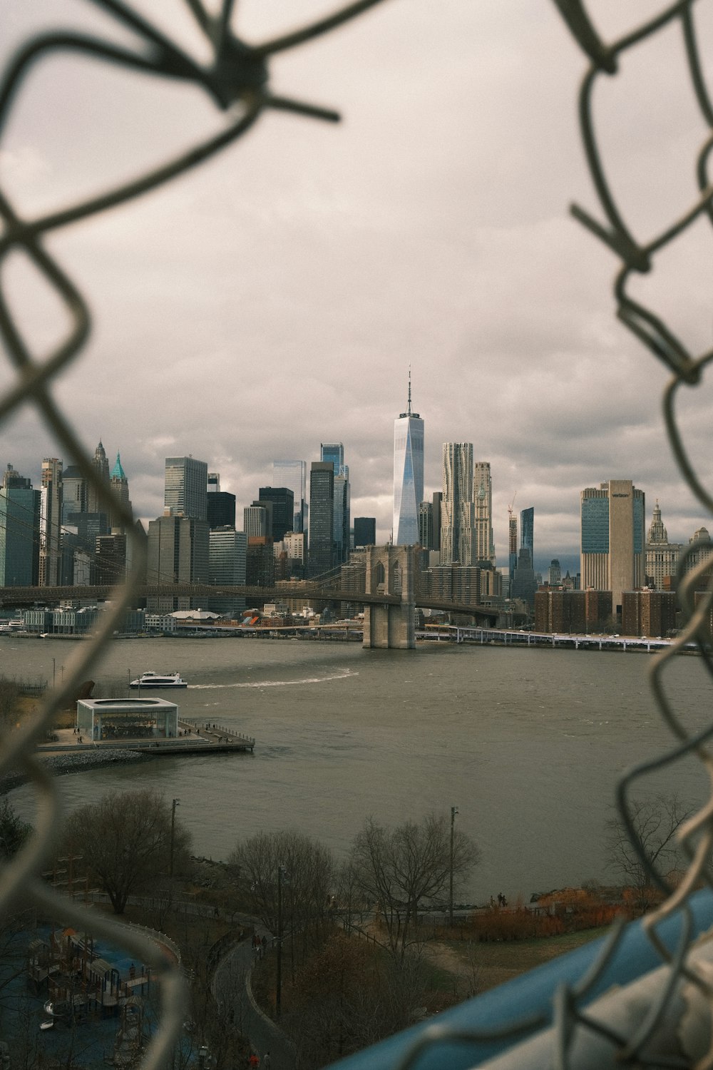 a view of a city skyline through a chain link fence