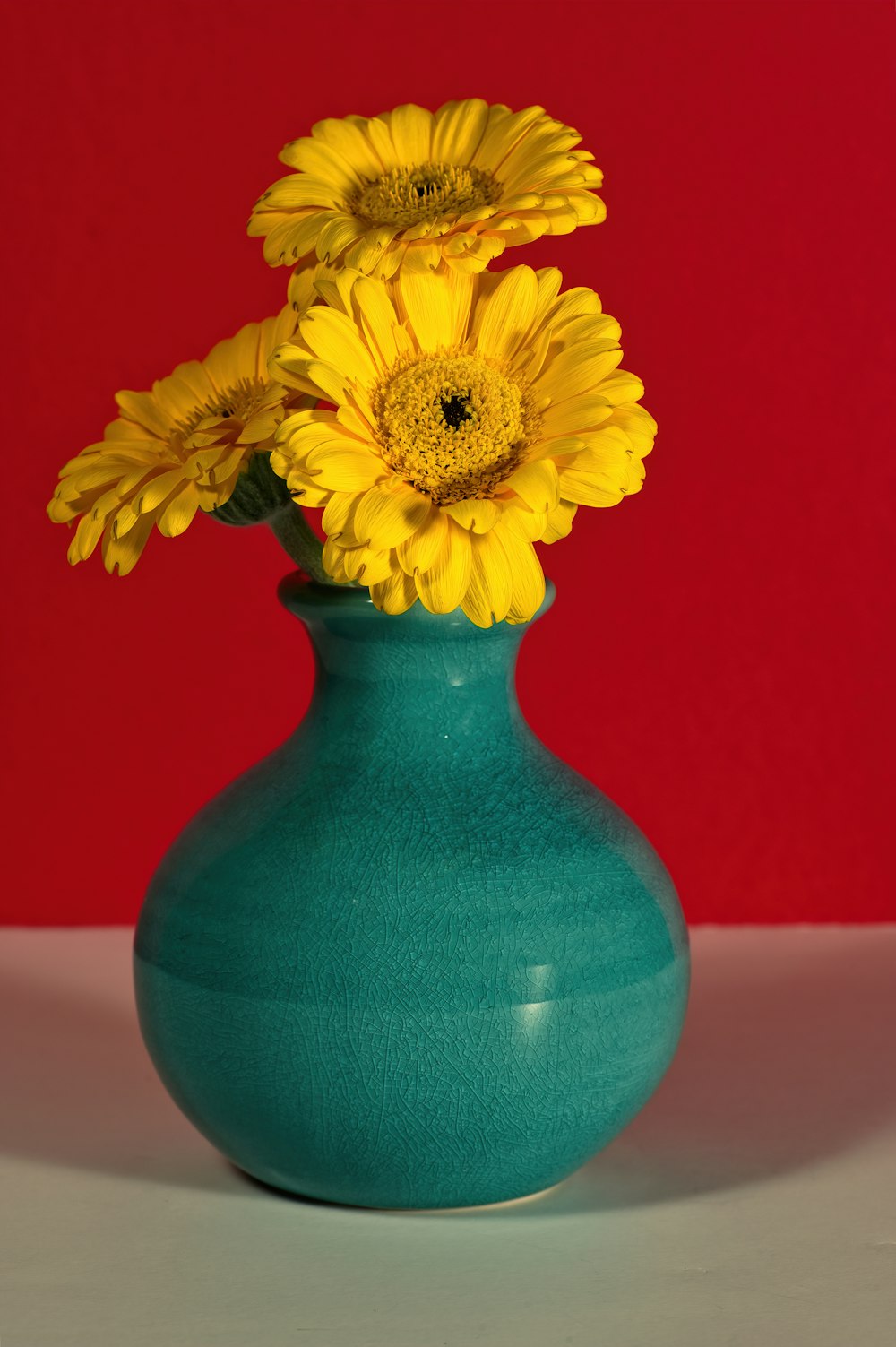 a green vase with yellow flowers in it