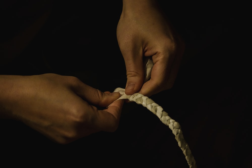 a person tying a white rope with their hands