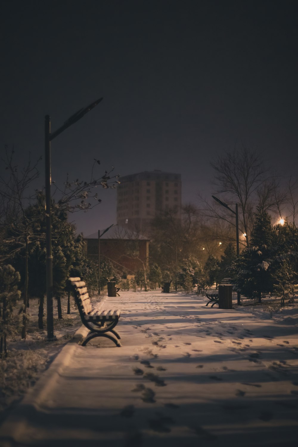 a park bench is covered in snow at night