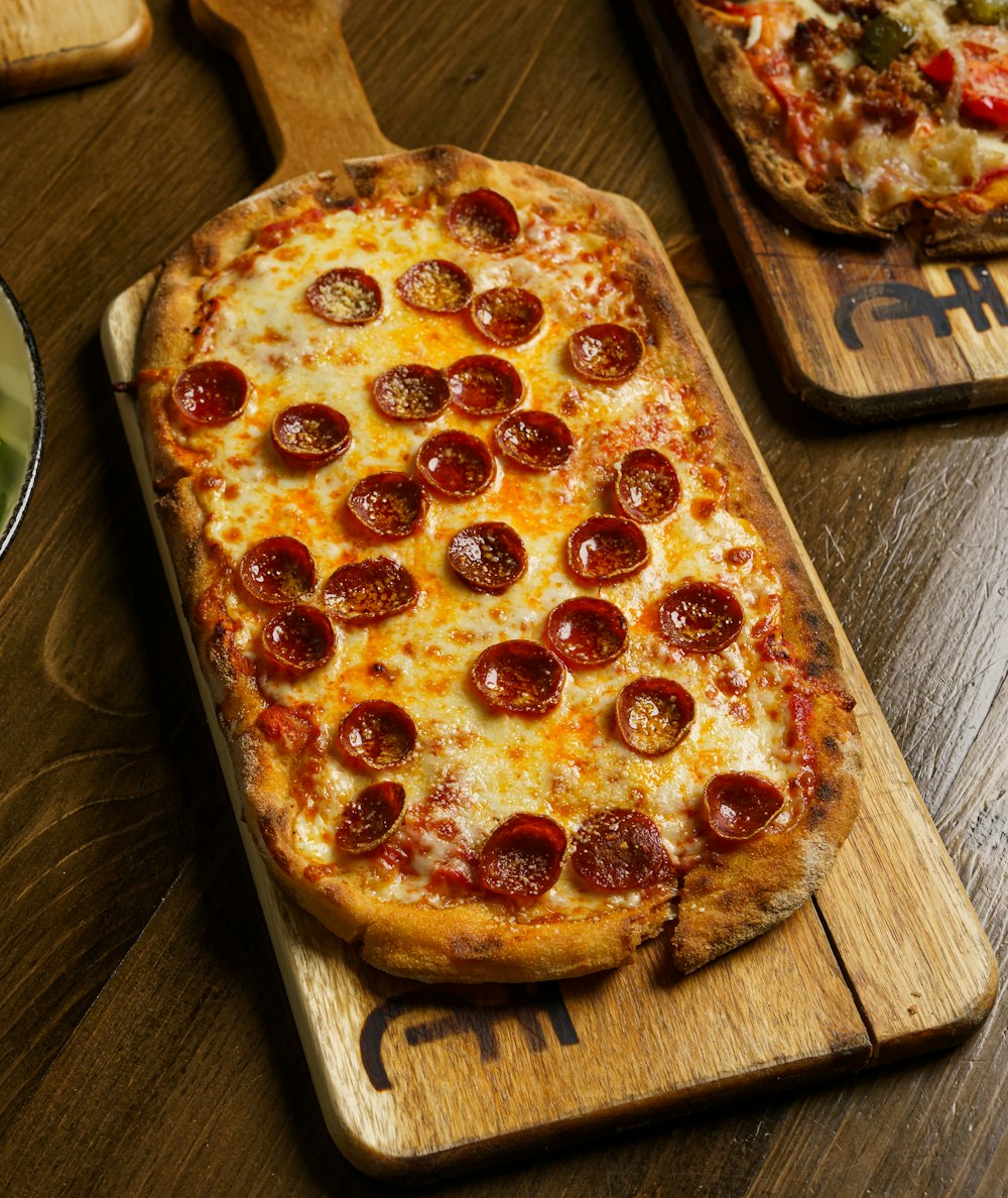 a wooden cutting board topped with a pepperoni pizza