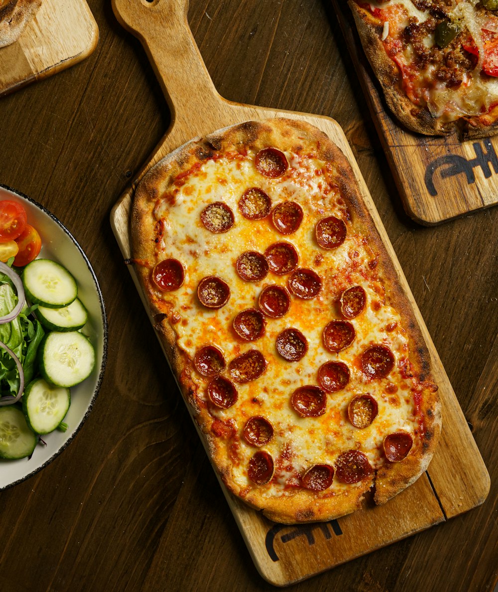 a pizza on a cutting board next to a salad