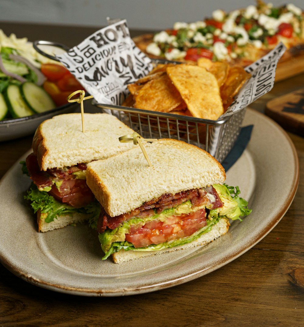 a sandwich on a plate next to a basket of chips