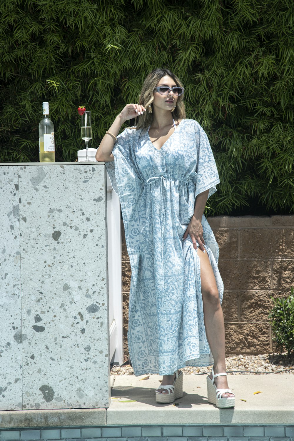 a woman in a blue dress standing next to a pool